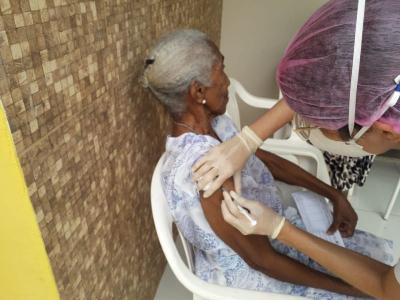 agente de saúde aplica vacina em idosa
