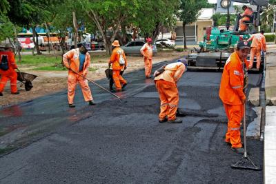 homens trabalham em asfaltamento de rua