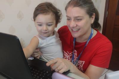 mulher e criança olham tela de computador